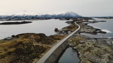 Atlantic-Ocean-Road-In-The-Island-Of-Skarvoy-In-Norway-With-Snowy-Alps-In-Background