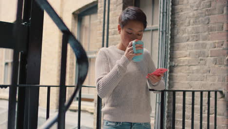 Schöne-Asiatische-Frau,-Die-Draußen-Ihr-Smartphone-Benutzt-Und-In-Einer-Pause-Kaffee-Trinkt
