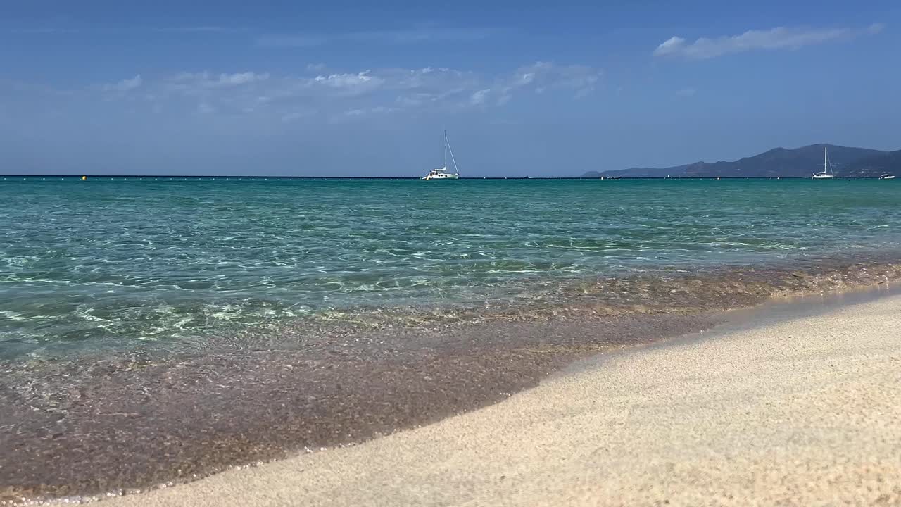 프랑스 코르시카의 백그라운드에서 청록색 바다 물과 yacths 및 범선이있는 saleccia 목가적 인 모래 해변의 낮은 각도 지상 pov