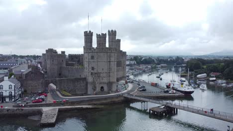 antiguo caernarfon castillo galés puerto pueblo vista aérea medieval frente al mar punto de referencia lento bajo izquierda órbita tiro