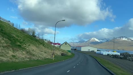countryside road and small residential neighborhood in landscape of iceland, driver's pov of homes and business buildings