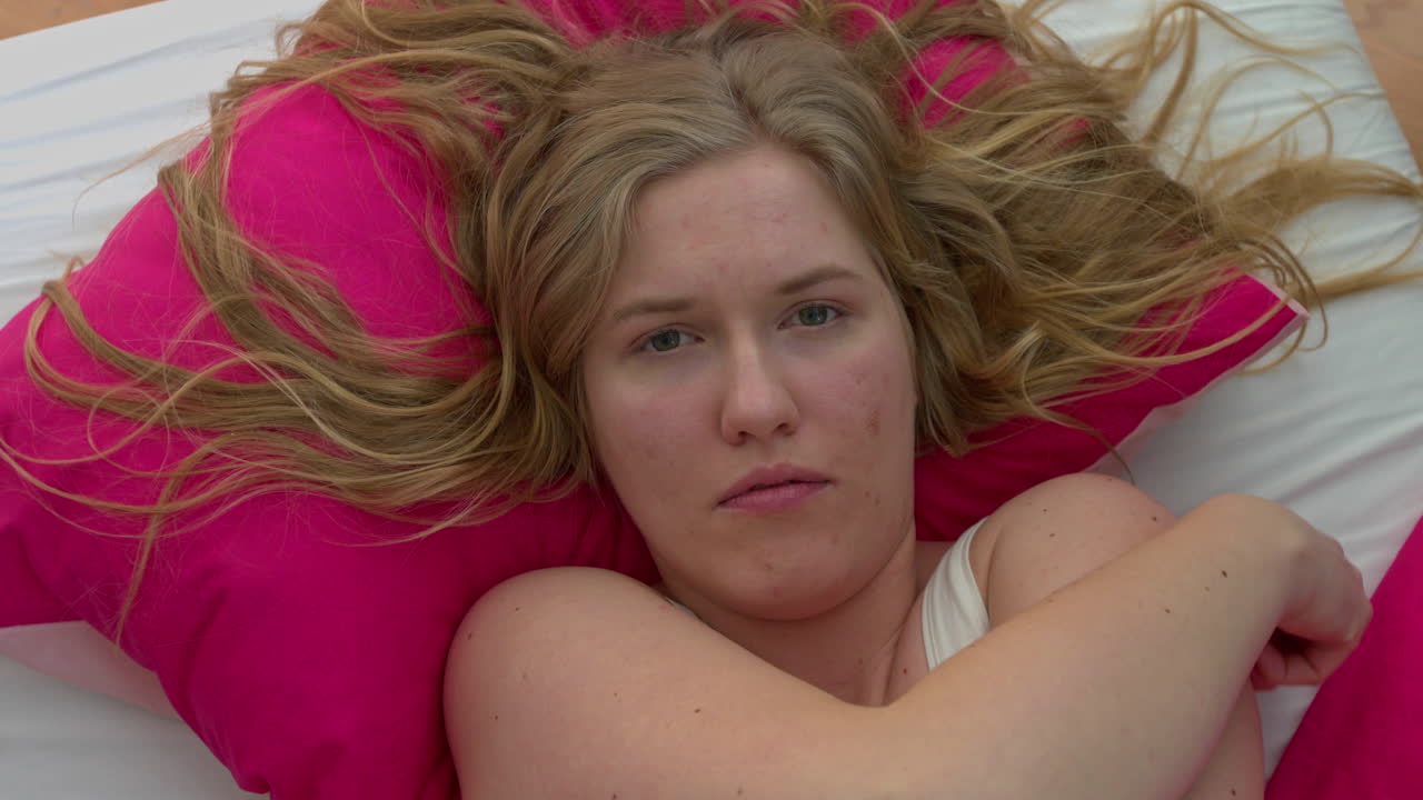 una mujer triste yace en la cama