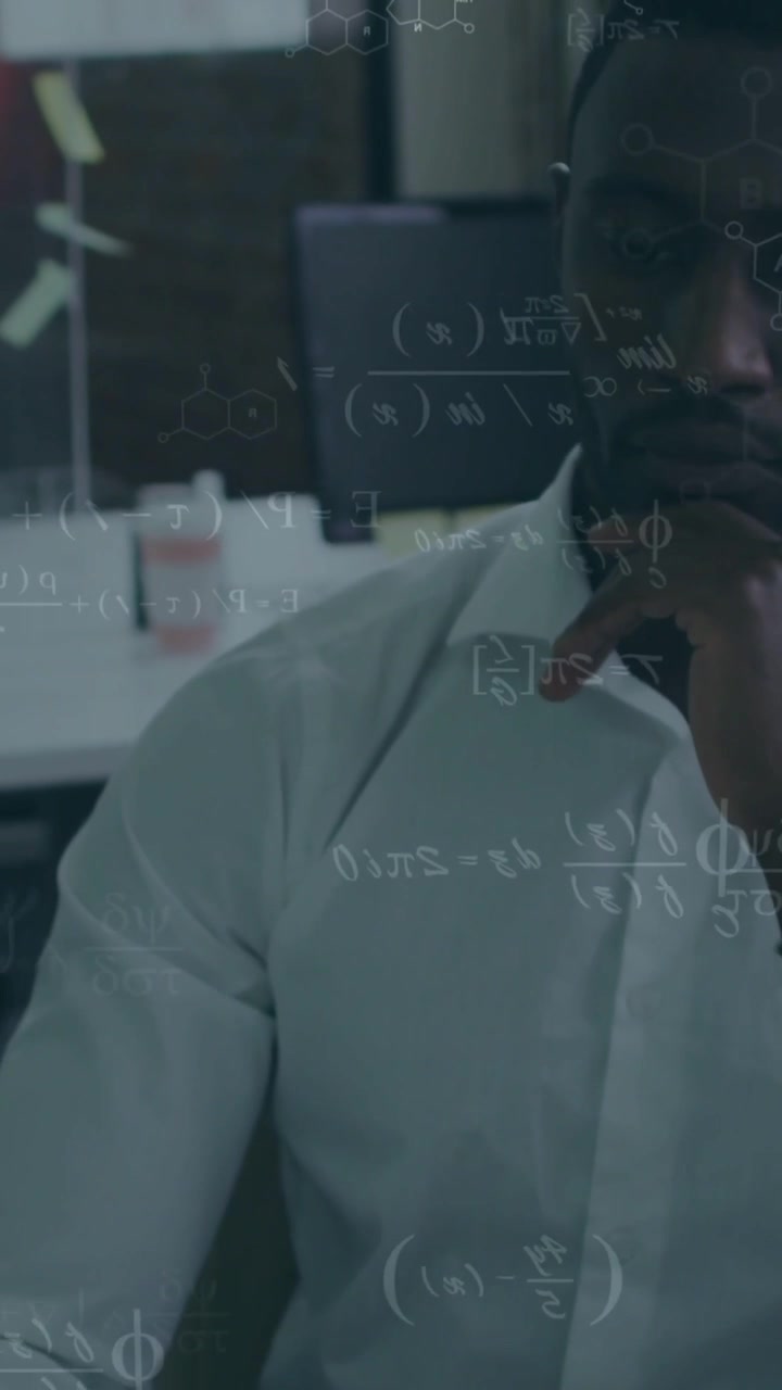 Vertical video: Teacher at desk studying math on glass, camera pulling back, hand at chin analyzing