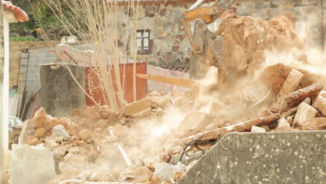 excavadora transportando escombros de una casa de hormigón demolida