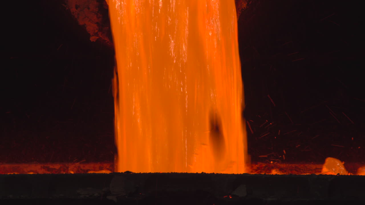 Metallo fuso incandescente che si riversa in un ambiente industriale buio