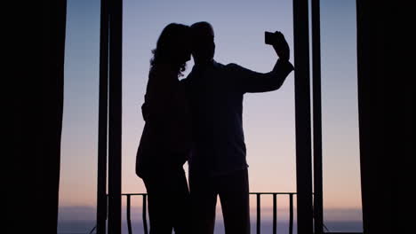 silueta pareja de ancianos felices tomando fotos juntos usando el teléfono inteligente disfrutando de una jubilación exitosa compartiendo vacaciones en las redes sociales al atardecer