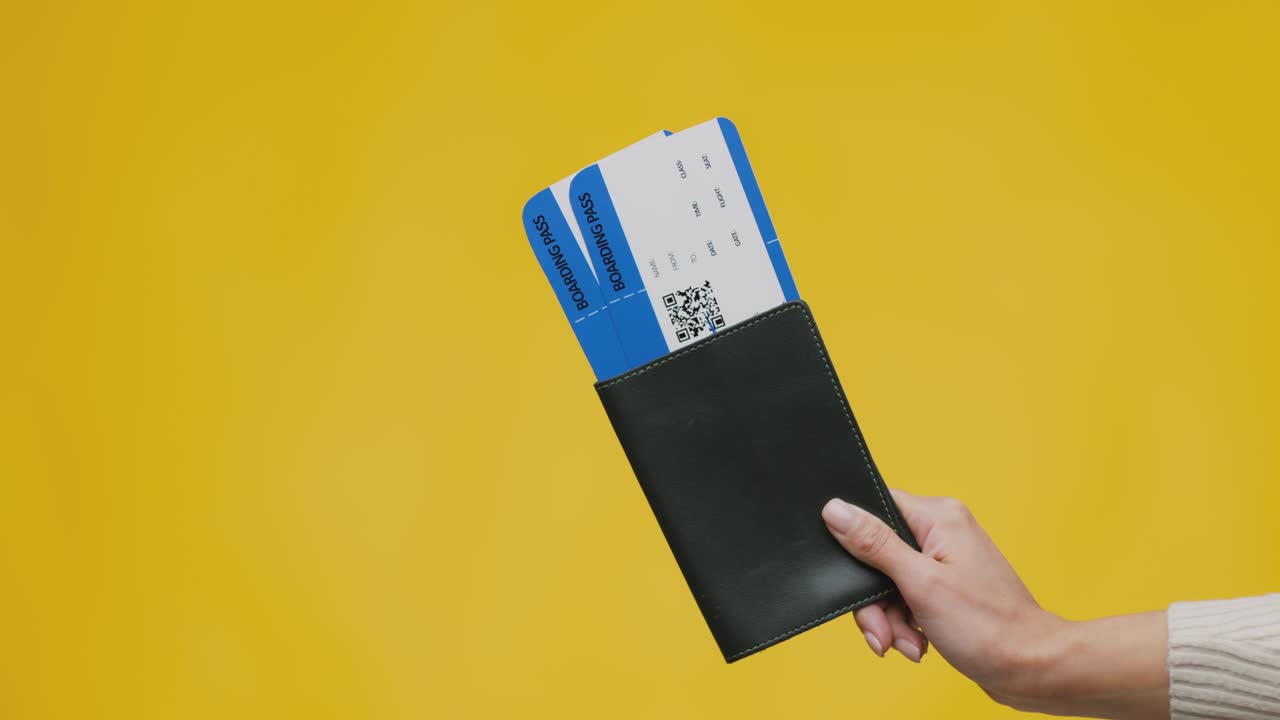 turismo internacional. mano femenina con pasaporte y dos boletos de avión, lista para las vacaciones, fondo amarillo