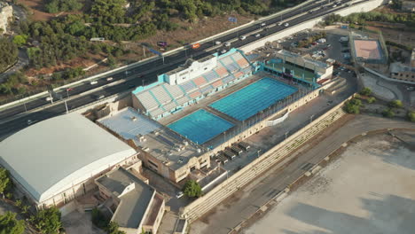 Swimming-Pool-close-to-Freeway-in-Malta,-Aerial-Wide-View-Establisher,-SEPTEMBER-9th-2020