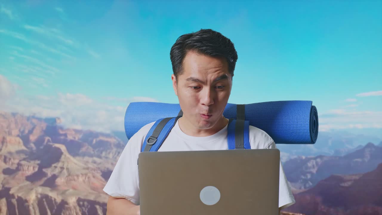 Close Up Of Asian Male Hiker With Mountaineering Backpack Looking At A Laptop And Saying Wow While Traveling At The Top Of Mountain