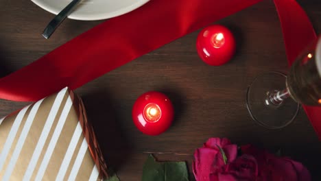 closeup romantic table with chocolate fudge present red candles glass of wine and champagne, pink roses bouquet