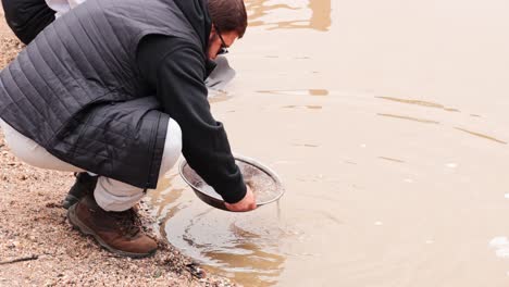 man panning for gold in muddy water