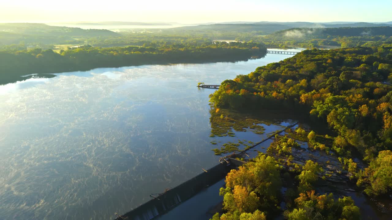 Costa alberata e acqua increspata sul Lago Sequoyah, calda luce del tramonto autunnale, ripresa aerea orbitale media che attraversa lo scaricatore, Wyman Arkansas USA