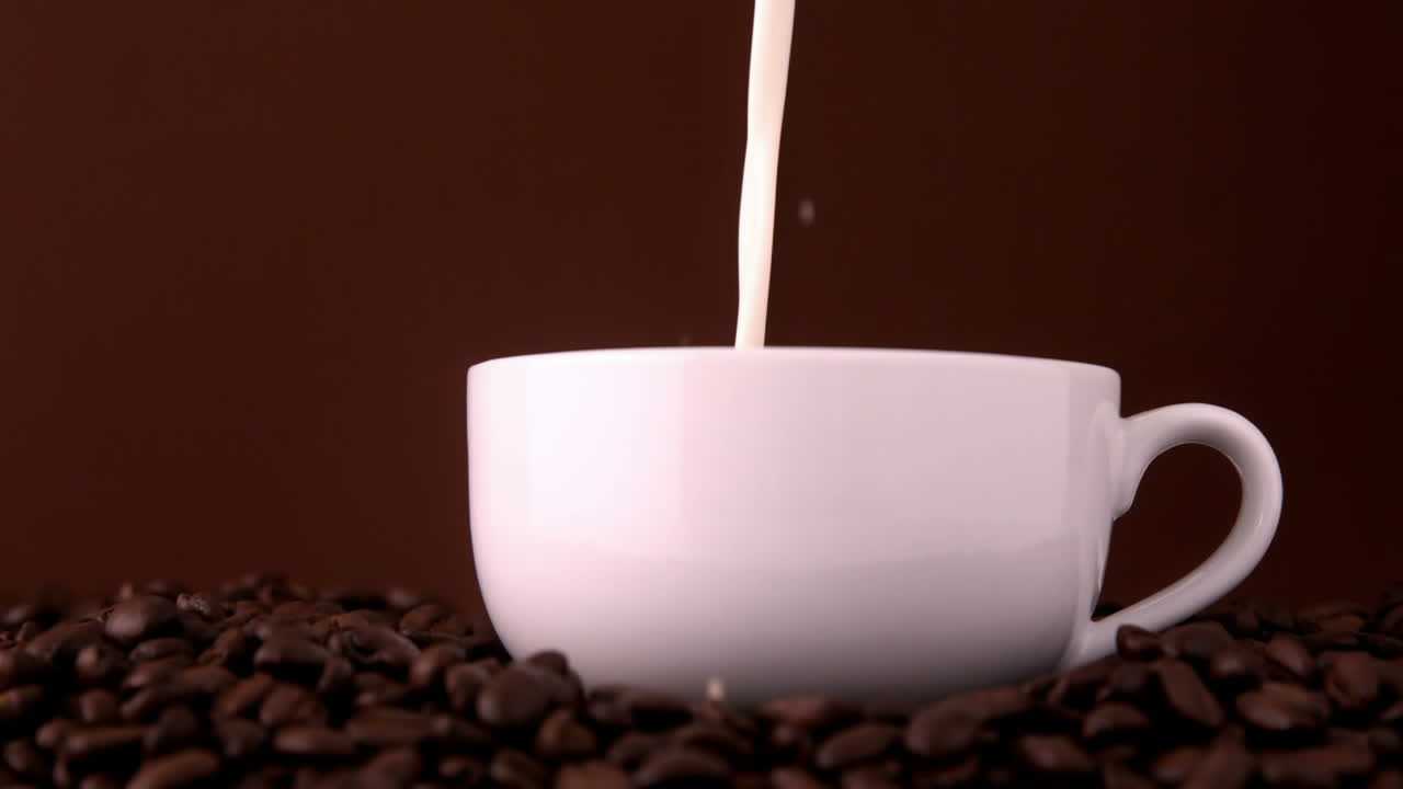 la leche se vierte en una taza de café blanca