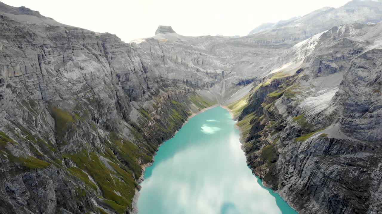 un paso elevado inverso sobre un excursionista que disfruta de la vista del lago limernsee en glarus, suiza, cuyas aguas color turquesa están rodeadas de altos picos y acantilados de los alpes suizos