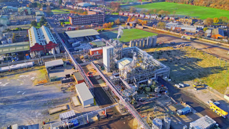 Aerial-footage-moving-towards-a-large-industrial-chemical-plant,-showing-pipelines,-metal-structures,-cooling-towers-and-chemical-storage