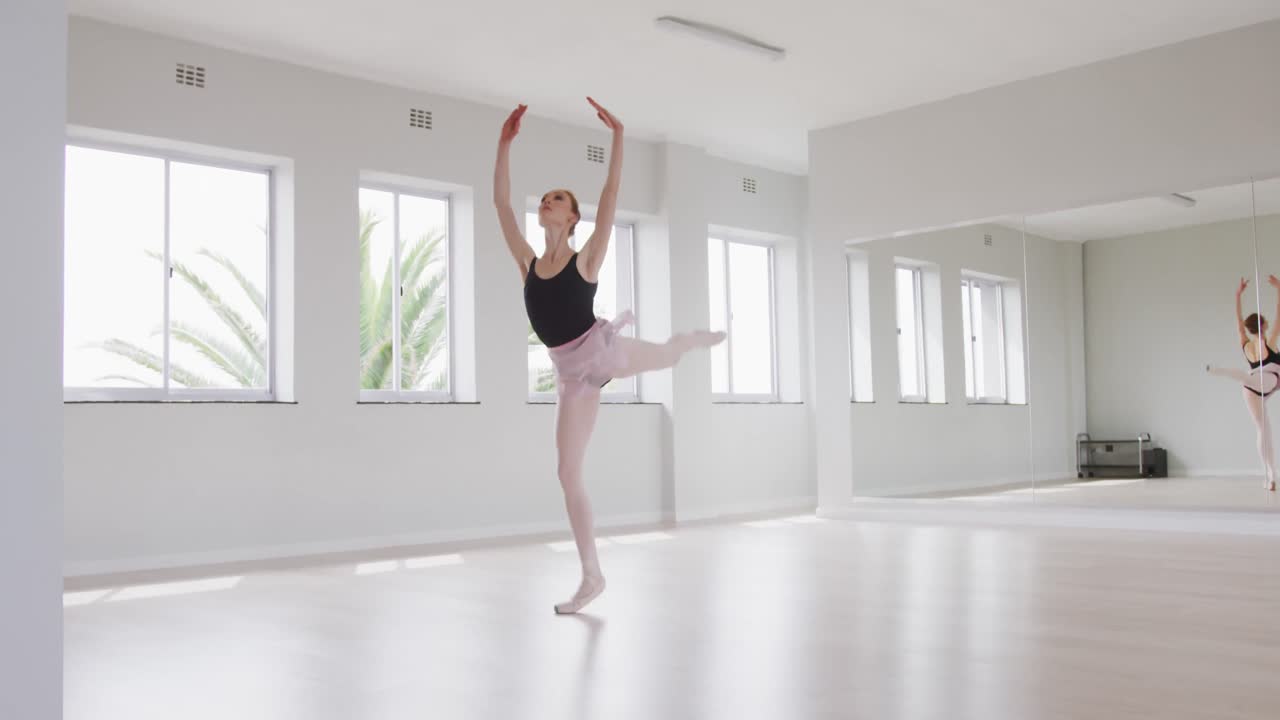 Bailarina caucasiana praticando balé durante uma aula de dança em um estúdio iluminado