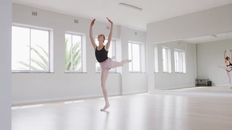 caucasian female ballet dancer practicing ballet during a dance class in a bright studio