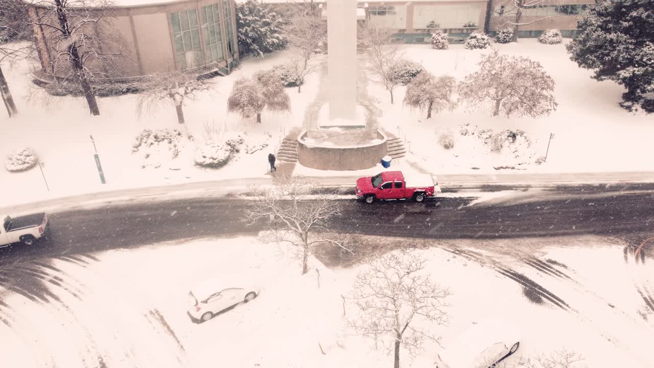 aerial view of a red truck plowing snow, clearing the road in winter time