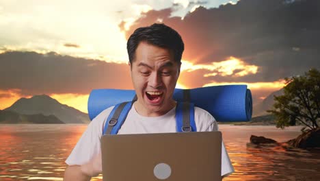 close up de un excursionista masculino asiático con una mochila de montañismo mirando una computadora portátil y gritando meta celebrando el éxito en un lago