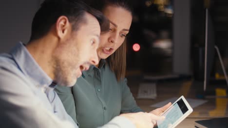 caucasian adult woman and man working late together at the office.