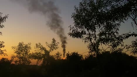 flame and black smokes rising from rural village in ukraine, vibrant sunset time