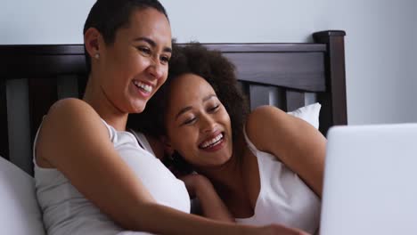 lesbian couple using laptop in bedroom
