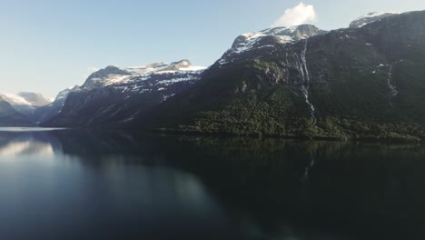 Snow-covered-peaks-and-lake-of-Lovatnet-in-Norway,-pan-left-view