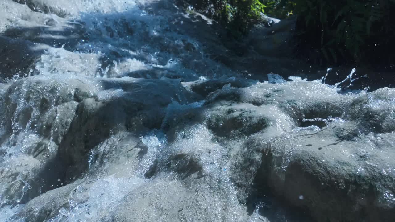 Primo piano di acqua fresca che scorre a cascata su rocce bianche nella natura