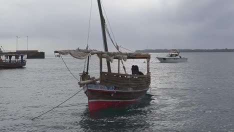 Dhau-Boot-Ankerte-In-Der-Bucht,-Und-Ein-Mann-Schüttete-Wasser-Aus-Dem-Boot-Ins-Meer