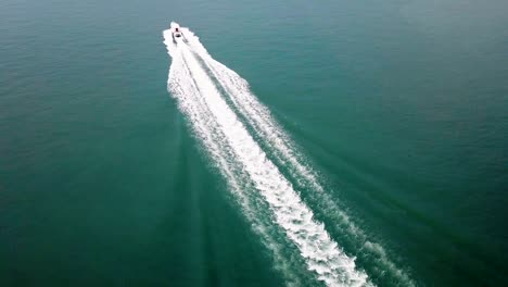 aerial - top down tracking shot of a bigger speed boat cruising on water