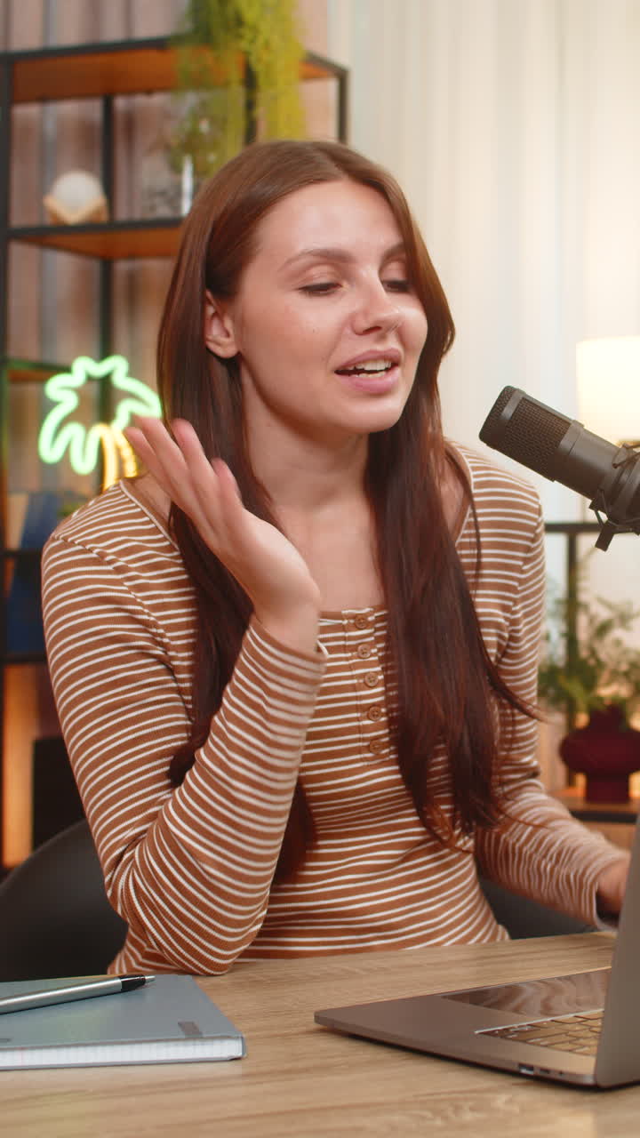 Young woman records vlog on studio mic greets audience shares useful info and invites to subscribe