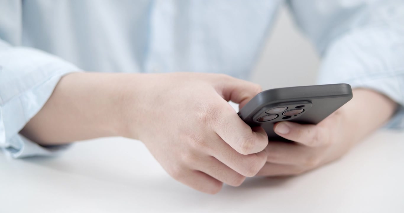 Una persona interagisce attivamente con il proprio smartphone in uno spazio interno luminoso, evidenziando la moderna comunicazione digitale