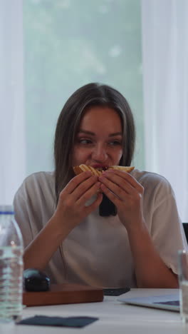 estudiantes hambrientos comen sándwiches frescos viendo conferencias en línea en la computadora portátil. mujer con discapacidad disfruta de un bocadillo con su mejor amiga sentada en la mesa de primer plano