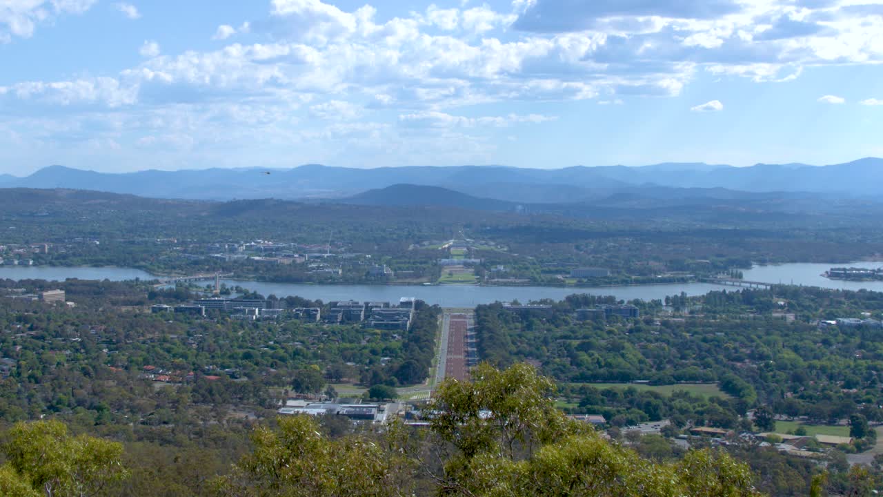Wide panoramic shot of Canberra city, Lake Burley Griffin, and mountains under a blue sky