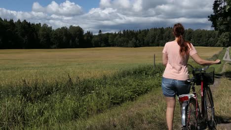 Mujer-Caminando-Con-Bicicleta-En-El-Campo-Camino-Rural