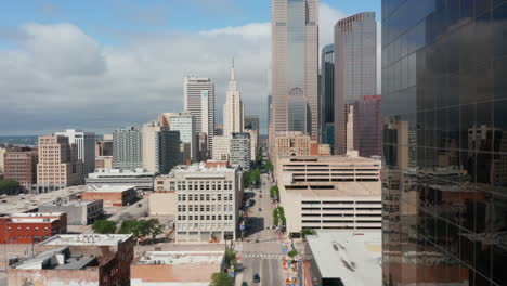 Landing-footage-of-tall-modern-downtown-buildings-along-long-straight-street.-Dallas,-Texas,-US