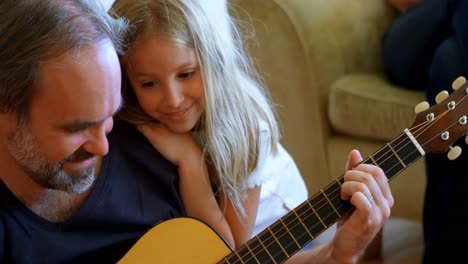 Vater-Spielt-Gitarre-Mit-Ihrer-Tochter-Im-Wohnzimmer-4K