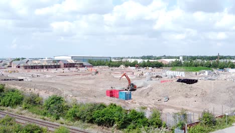 UK-town-housing-development-working-foundation-construction-site-aerial-view-zoom-in-towards-machinery