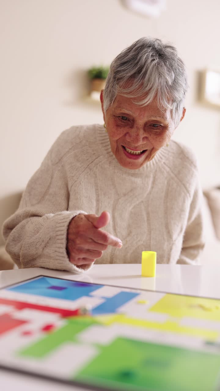 Happy Elderly Woman Playing a Colorful Board Game at Home