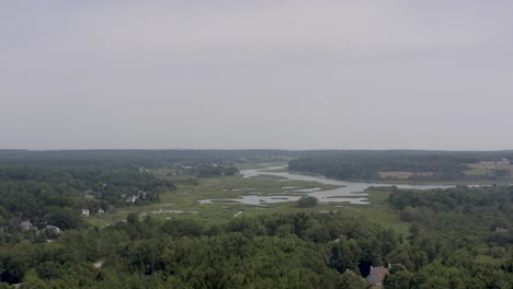 Drone-flying-over-neighborhood-with-marsh-in-background-in-Scarborough,-Maine