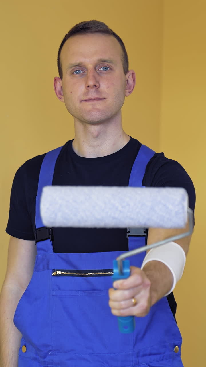 Giovane pittore professionista si prepara al lavoro. Un bell'uomo esegue la ristrutturazione di un appartamento. Video verticale.