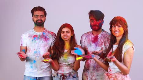 four indian students painted in colors celebrating holi festival in studio white isolate background