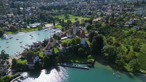 push out drone shot of the city of spiez with the castle, the port and thun lake