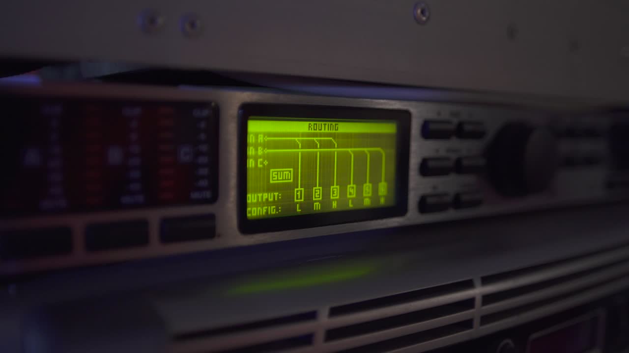 Close up green light screen of routing on digital sound console of professional audio equipment. Levels on screen, buttons on the panel.