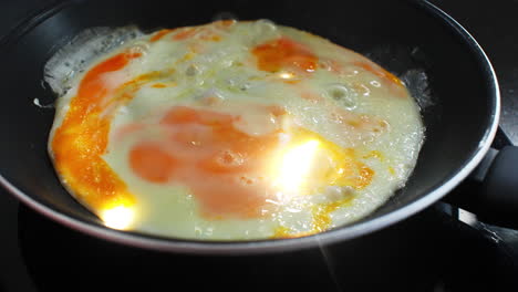 sunny side up egg sizzling on hot pan, yellow yolk gradually transforming while bright flames dance underneath cooking surface and creating appetizing breakfast moment