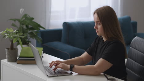 young woman dressed black t-shirt is chatting in social nets by laptop with wireless internet connection relaxing at home at weekends