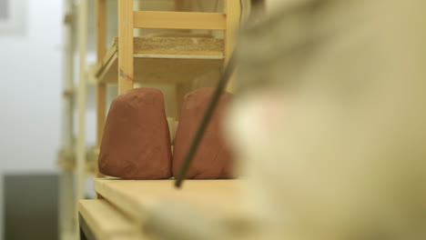 male hands removing raw clay block from studio workshop shelving preparing project