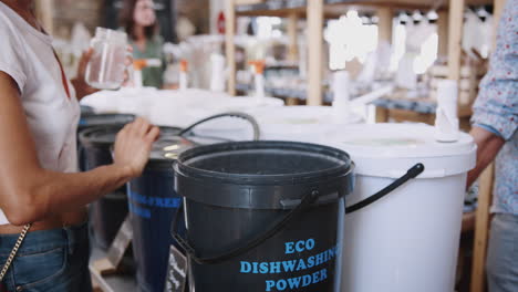 woman filling container with dishwasher powder in plastic free grocery store