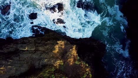 rising aerial shot of waves crashing into a rocky cove on the california coast