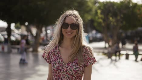 la cámara sigue a una joven rubia vestida en un soleado día de verano.